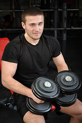 Image showing young man sits after workout in gym