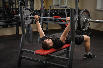 Image showing young man doing bench press workout in gym