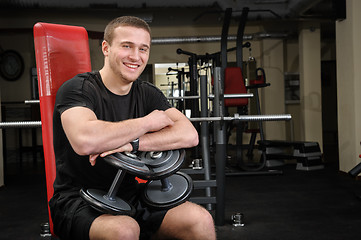 Image showing young man sits after workout in gym