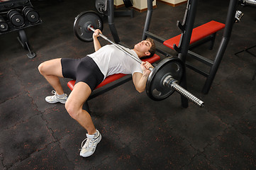 Image showing young man doing bench press workout in gym