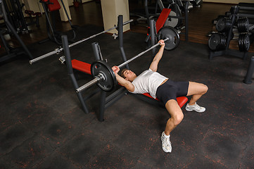 Image showing young man doing bench press workout in gym