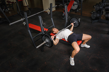Image showing young man doing bench press workout in gym
