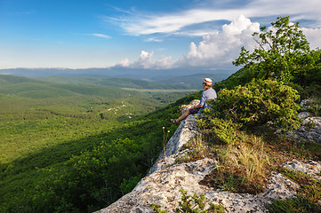 Image showing Hiking man in rays of sunset sitting at the edge