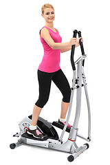 Image showing young woman doing exercises on elliptical trainer