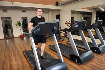 Image showing young man running at treadmill in gym