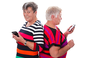 Image showing Two senior women communicating with cellphones