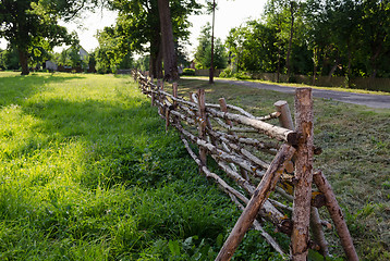 Image showing rural style twisted fence of branches along road 