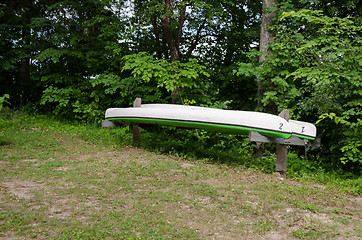 Image showing inverted canoes on wooden sticks dug into ground 