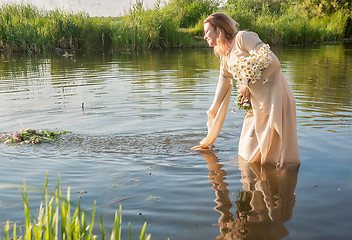 Image showing Attractive woman lowers wreath in water