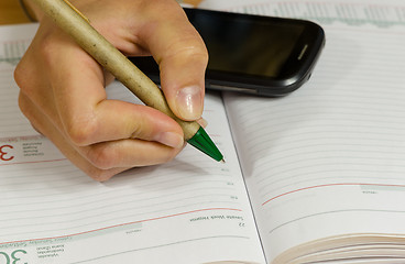 Image showing hand make write notes in notebook and smart phone 