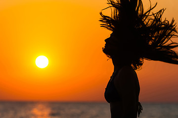 Image showing Silhouette of woman waving hair at sunset