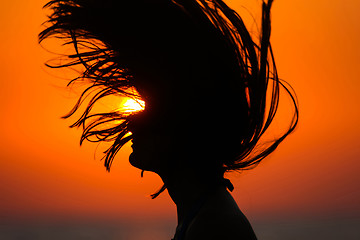 Image showing Silhouette of woman tossing hair at sunset