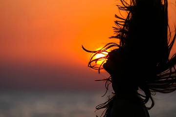 Image showing Silhouette of young woman waving hair at sunset