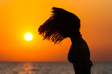 Image showing Young woman tossing hair at sunset