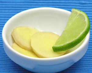 Image showing Ginger with lemon in a bowl of chinaware on blue