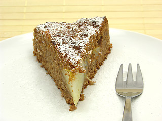 Image showing One slice of pear cake on a white plate dusted with powder sugar