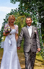 Image showing Happy just married couple under a rice rain