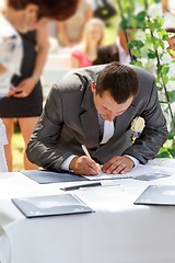 Image showing groom signing certificate in park 