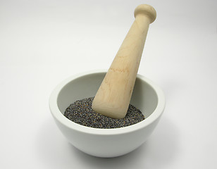 Image showing Pestling poppy seeds  in a bowl of chinaware