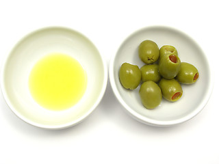 Image showing Two bowls of chinaware with olive oil and olives on white background