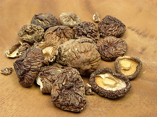 Image showing Dried shiitake arranged on a brown wooden plate