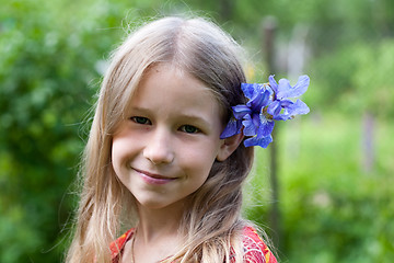 Image showing small girl with blue iris flower in her hair