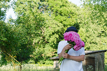 Image showing man hiding his face with peony bouquet garden  