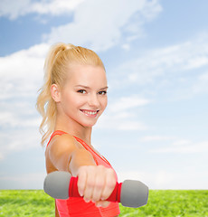 Image showing smiling beautiful sporty woman with dumbbell