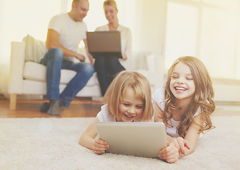 Image showing smiling sister with tablet pc and parents on back