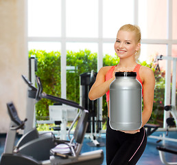 Image showing smiling sporty woman with jar of protein