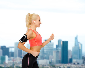 Image showing sporty woman running with smartphone and earphones
