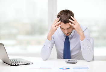 Image showing stressed businessman with laptop and documents