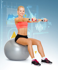 Image showing woman with dumbbells sitting on fitness ball