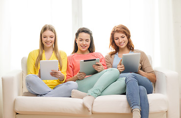 Image showing three smiling teenage girls with tablet pc at home