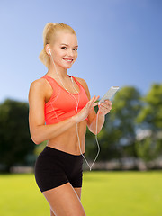 Image showing smiling sporty woman with smartphone and earphones