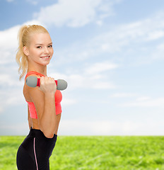 Image showing smiling beautiful sporty woman with dumbbell