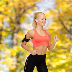 Image showing sporty woman running with smartphone and earphones