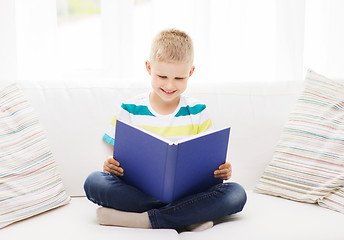 Image showing smiling little boy reading book on couch