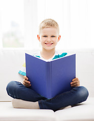 Image showing smiling little boy reading book on couch