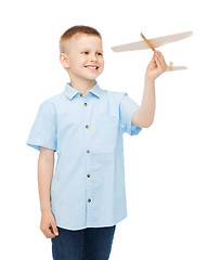 Image showing smiling little boy holding a wooden airplane model