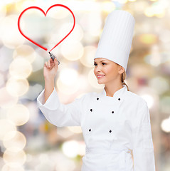 Image showing smiling female chef drawing red heart on air