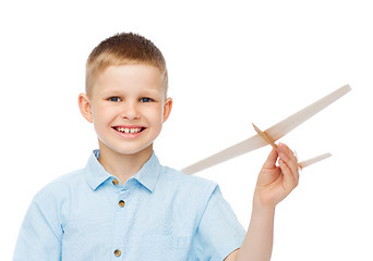 Image showing smiling little boy holding a wooden airplane model