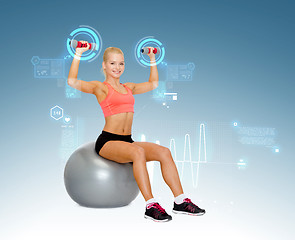 Image showing woman with dumbbells sitting on fitness ball