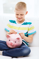 Image showing smiling little boy with piggy bank and money