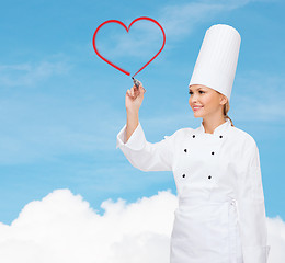 Image showing smiling female chef writing something on air