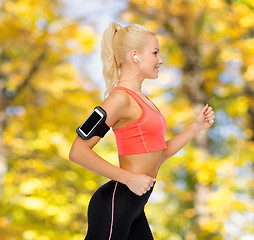 Image showing sporty woman running with smartphone and earphones