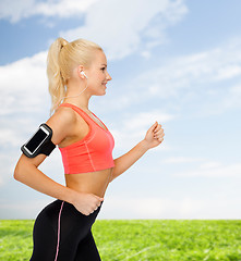 Image showing sporty woman running with smartphone and earphones