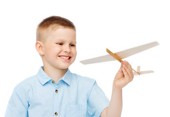 Image showing smiling little boy holding a wooden airplane model