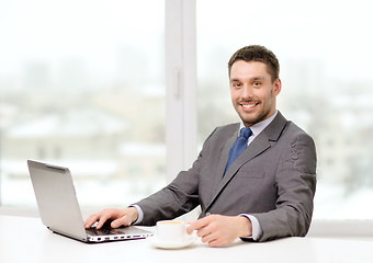 Image showing smiling businessman with laptop and coffee