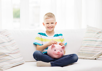 Image showing smiling little boy with piggy bank and money